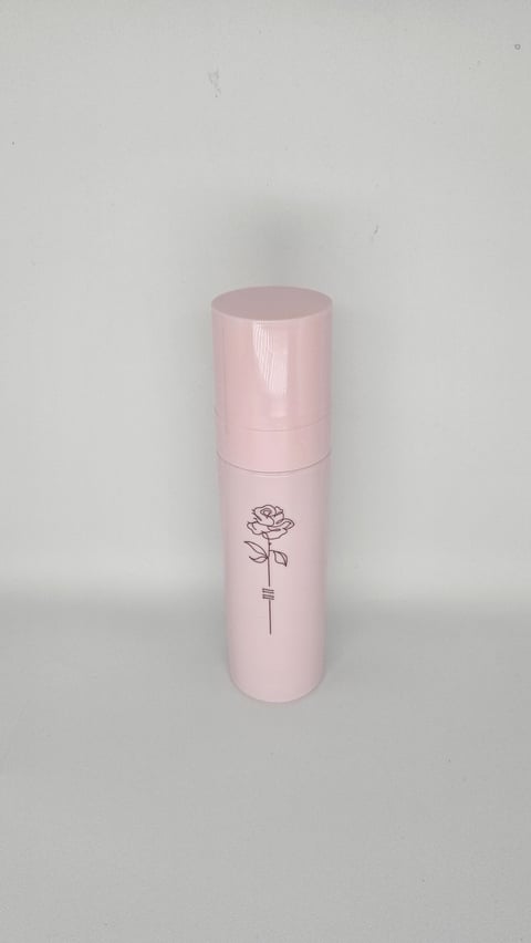Pink cylindrical spray bottle with rose line drawing, product photography on white background